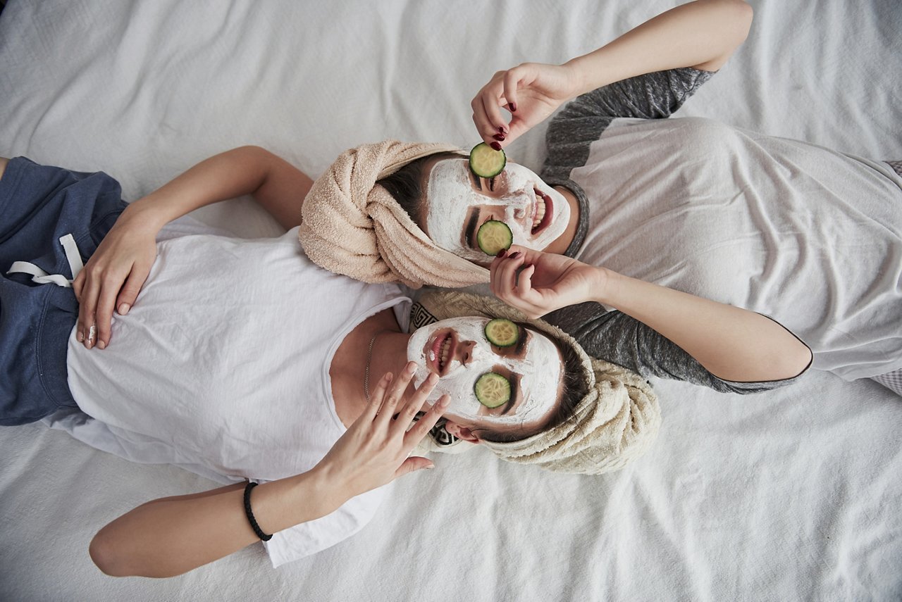 Taking off these things. Lying on the white bed. Top view. Conception of skin care by using white mask and cucumbers on the face.