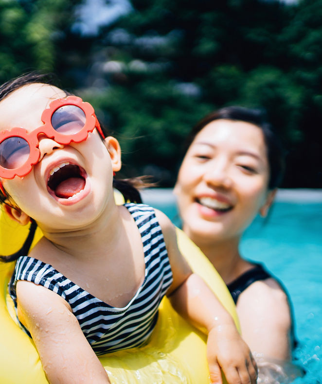 A mother is playing with her kid in the swimming pool during her stay at Langham Hotels. 