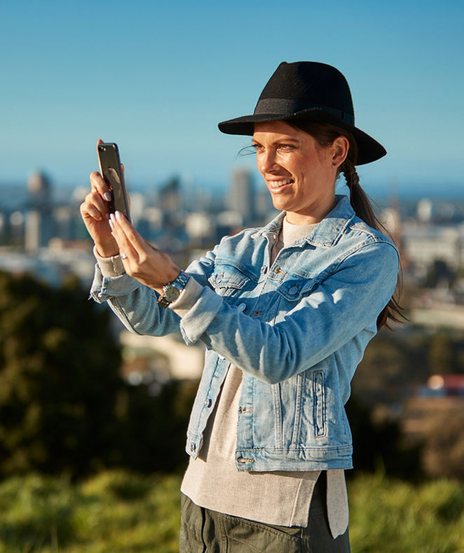 兩位女士正在愉快地使用朗廷卓逸會手機應用程式查看會員優惠。